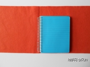 第二步：如图，将大块的毛毡对折，折出折痕，用笔记本进行对比，两侧的不织布至少要比笔记本长出6.5cm。