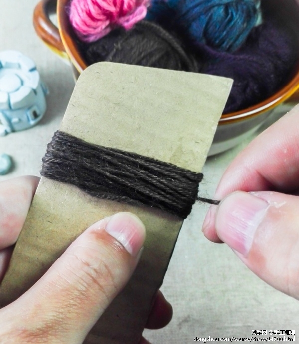 把毛线缠绕在纸板条上。